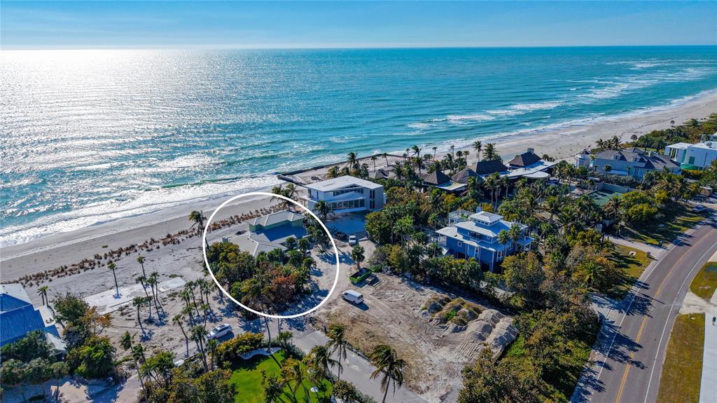 An aerial view shows beachfront houses and a concrete pier along a sandy coastline — 6601 GULFSIDE ROAD, LONGBOAT KEY, FL