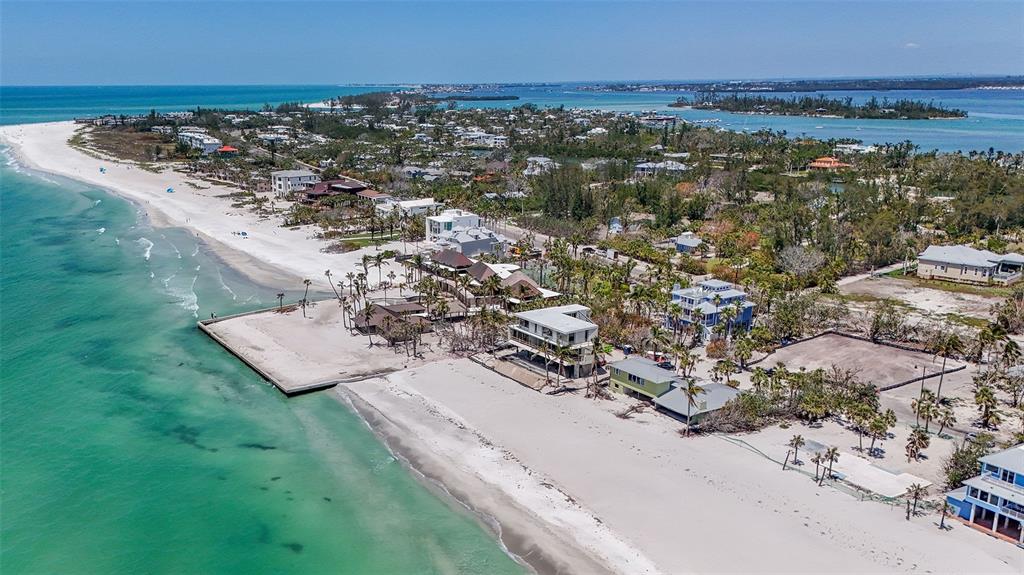 An aerial view shows a vacant beachfront lot situated between two houses along the coast — 6601 GULFSIDE ROAD, LONGBOAT KEY, FL