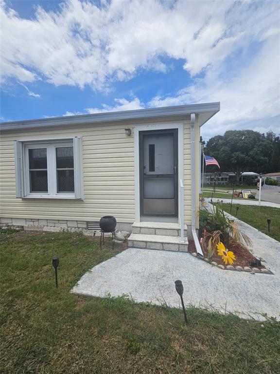 The exterior of a light yellow mobile home features a front door and a window — 475 PAPAYA CIRCLE, SEBASTIAN, FL