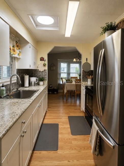 A kitchen with granite countertops, white cabinets, and stainless steel appliances leads into a dining area — 475 PAPAYA CIRCLE, SEBASTIAN, FL