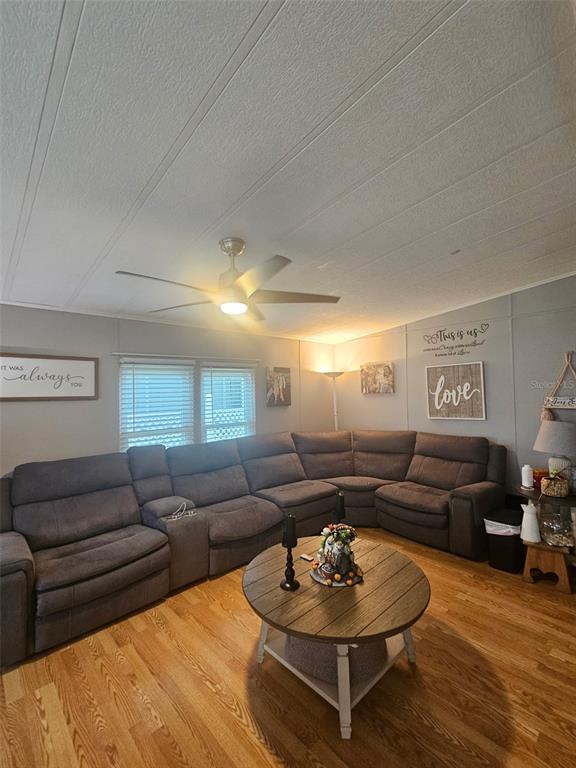 A living room features a large gray sectional sofa, a round wooden table, and hardwood floors — 475 PAPAYA CIRCLE, SEBASTIAN, FL