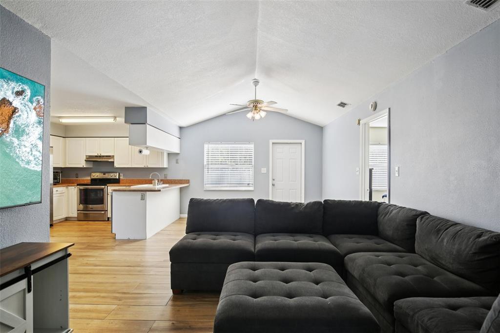 A living room with a sectional sofa and an open kitchen with white cabinets — 3501 W REYNOLDS STREET, PLANT CITY, FL