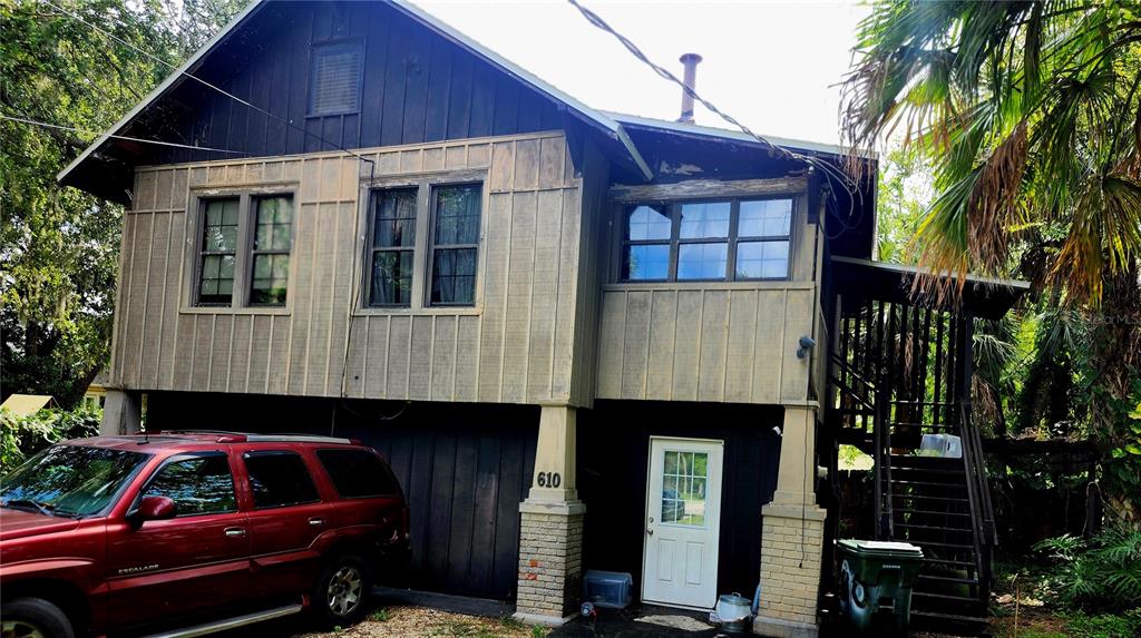 A two-story house with brown vertical siding, a red SUV, and an exterior staircase — 610 TANGLEWOOD STREET, DAYTONA BEACH, FL