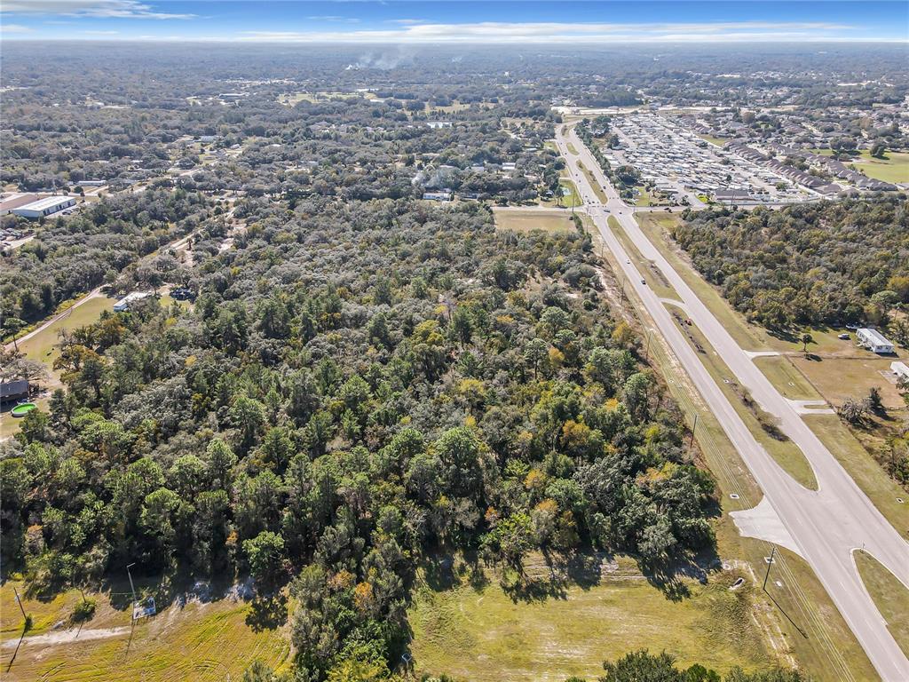 An aerial view shows a large wooded lot adjacent to a divided highway — 0000 LITTLE, HUDSON, FL