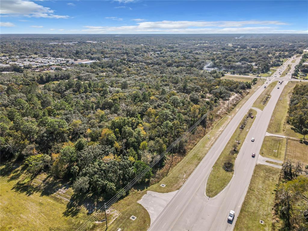 An aerial view shows a large, wooded lot adjacent to a multi-lane highway — 0000 LITTLE, HUDSON, FL