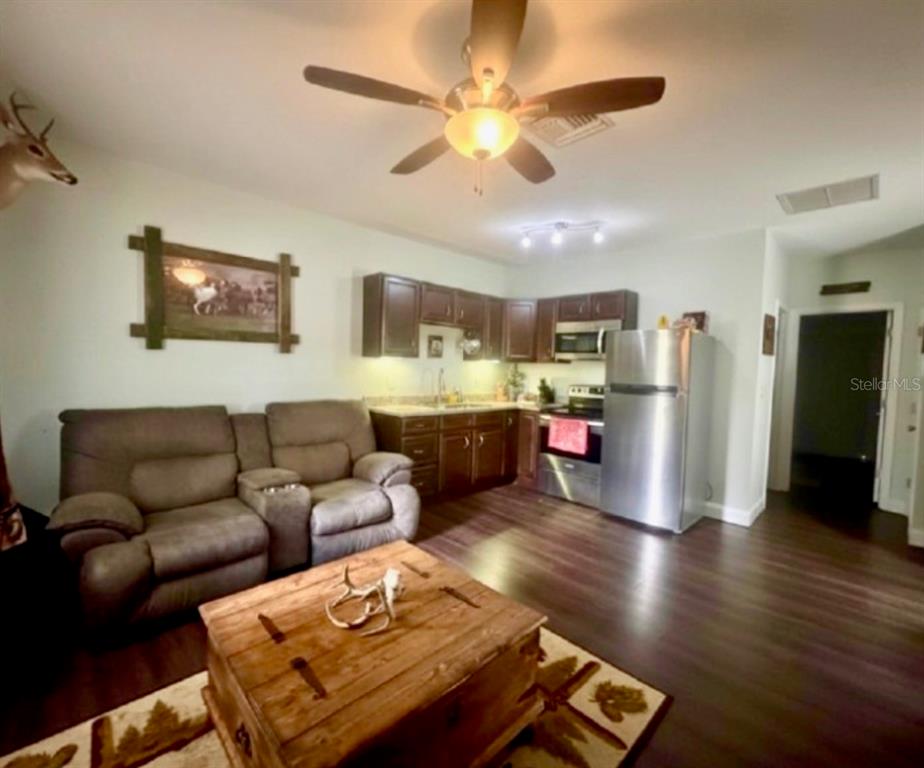 A living room with a brown sofa and wooden coffee table opens to a kitchen — 117 S MANATEE AVENUE, ARCADIA, FL