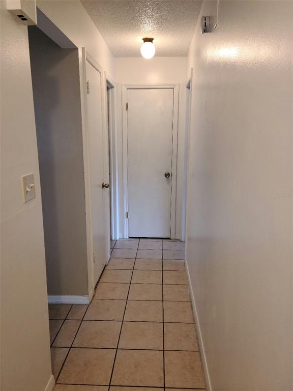 A narrow hallway features light-colored tile flooring, white walls, and a central ceiling light fixture — 2712 TORTOISE CV, WINTER PARK, FL