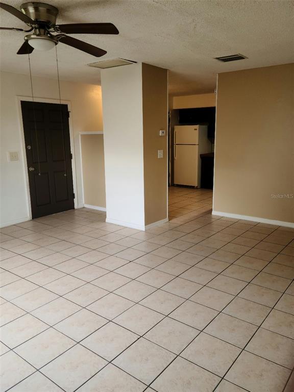 A room with light-colored tile flooring, a ceiling fan, and a view into a kitchen — 2712 TORTOISE CV, WINTER PARK, FL