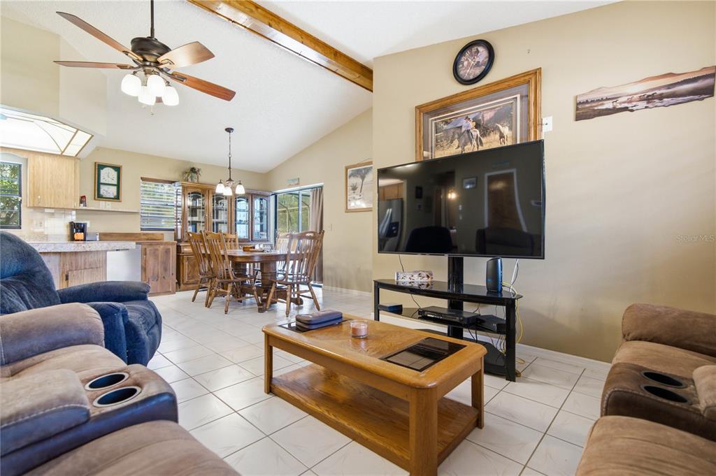 A living room with tile floors, a wooden coffee table, and an open dining area — 11423 LINDEN DRIVE, SPRING HILL, FL