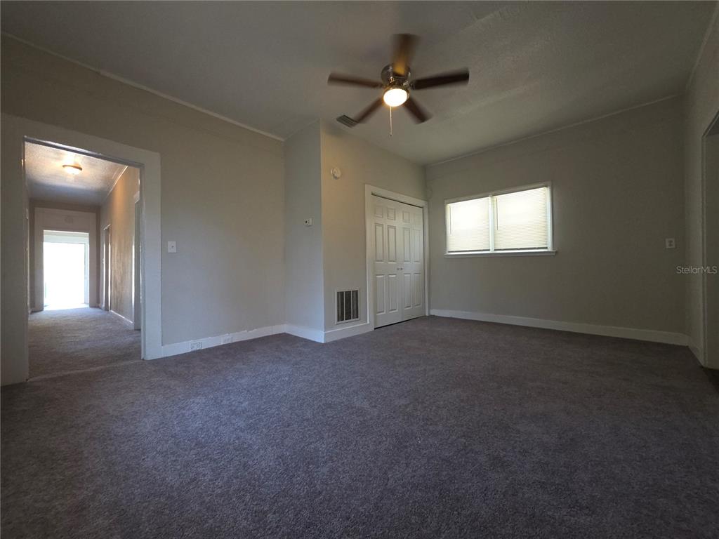 A carpeted bedroom features a ceiling fan, a closet with double doors, and a window — 2110 W 41ST STREET, JACKSONVILLE, FL