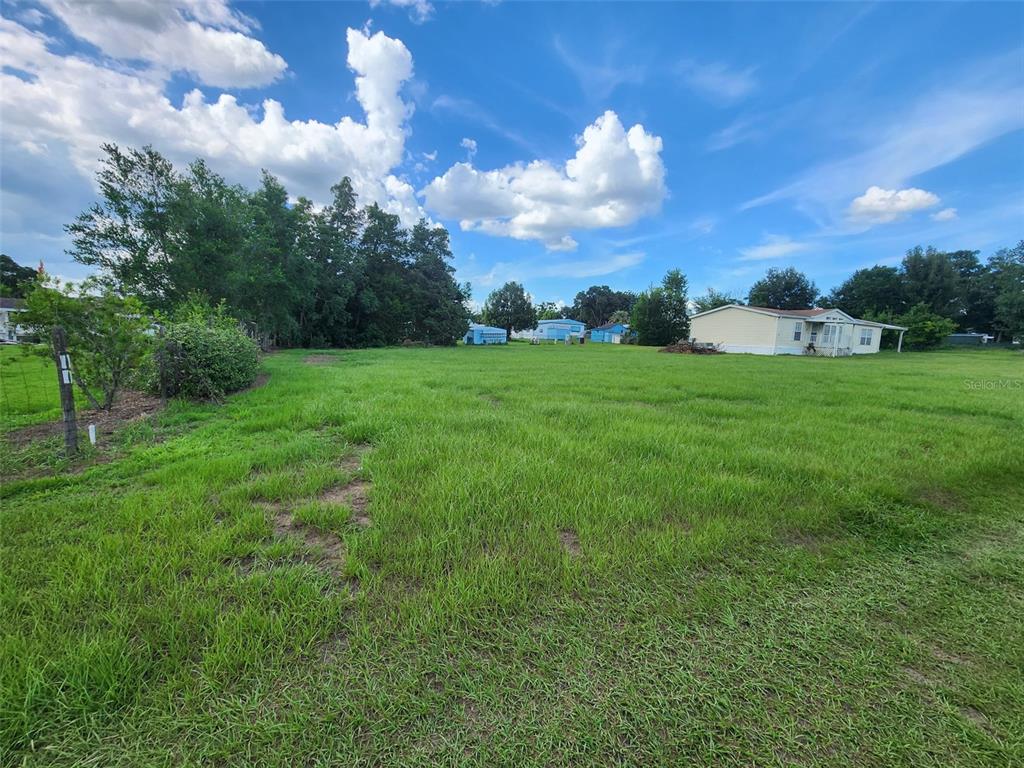 A grassy, open lot features a mobile home in the distance under a cloudy sky — 4237 E NEBRASKA LN, HERNANDO, FL