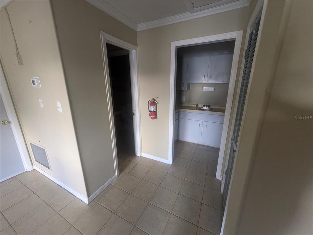 A tiled hallway leads to a small kitchenette with white cabinets and a fire extinguisher — 247 W MAIN STREET, APOPKA, FL