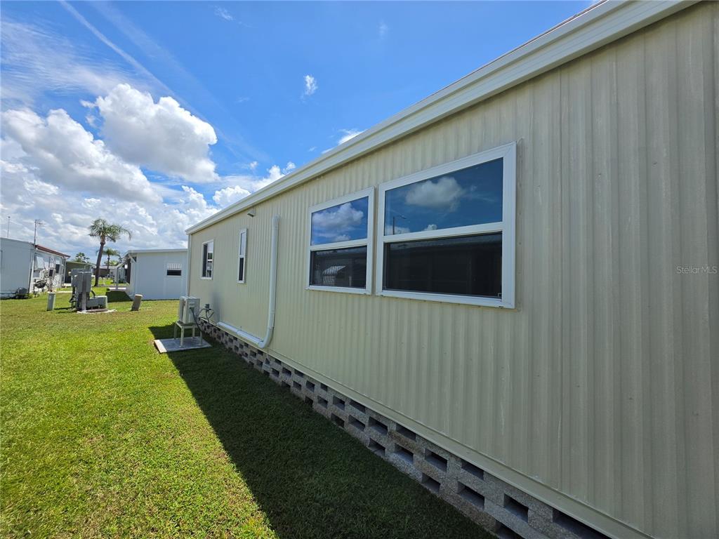 The exterior side of a light-colored manufactured home features a concrete block foundation — 10924 HERITAGE DRIVE, PORT RICHEY, FL