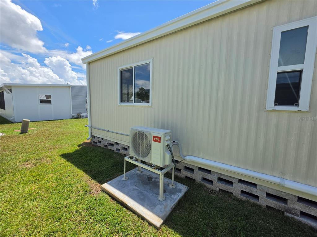 The exterior of a mobile home features a TCL air conditioning unit on a concrete pad — 10924 HERITAGE DRIVE, PORT RICHEY, FL