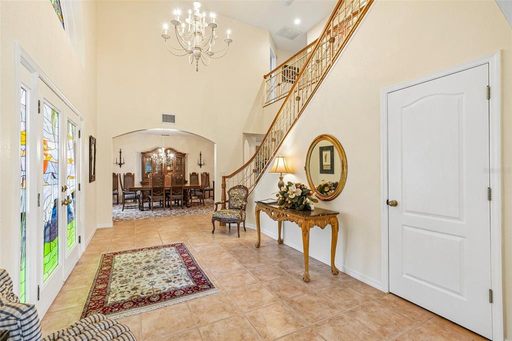 A grand foyer features a tiled floor, a curved staircase, and a view into the dining room — 5198 LEGEND HILLS LANE, SPRING HILL, FL
