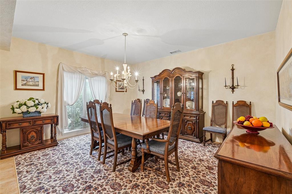 A formal dining room features a wooden table, chairs, a hutch, and patterned wall-to-wall carpeting — 5198 LEGEND HILLS LANE, SPRING HILL, FL