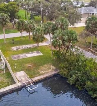 An aerial view of a waterfront lot with palm trees, concrete pads, and a boat lift — 6807 EDGEWATER DRIVE, NEW PORT RICHEY, FL