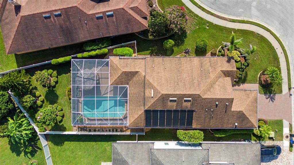 An aerial view of a house with a shingled roof, solar panels, and a screened pool — 1016 KETZAL DRIVE, TRINITY, FL