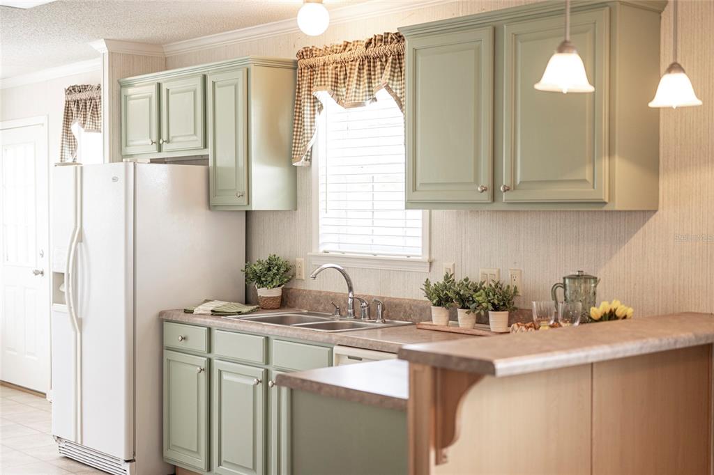 A kitchen features sage green cabinets, a white refrigerator, and a laminate countertop with sink — 2 HOLLAND DRIVE UNIT 39E, PUNTA GORDA, FL