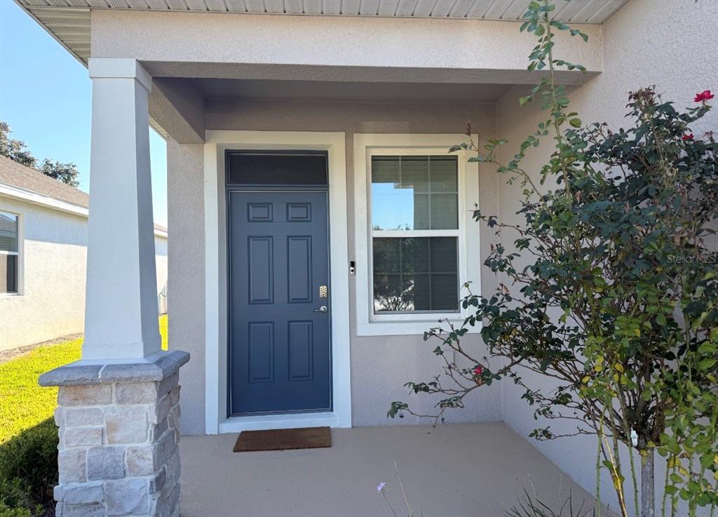 A blue front door with a transom window sits beside a window on a covered porch — 5450 NW 46TH LANE ROAD, OCALA, FL