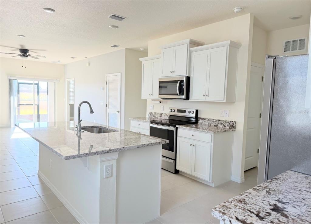 A kitchen with white cabinets, granite countertops, a center island, and stainless steel appliances — 5450 NW 46TH LANE ROAD, OCALA, FL