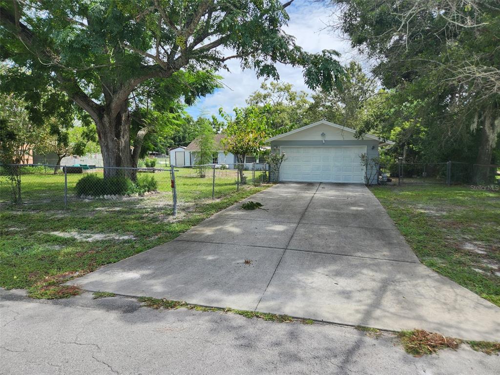 A concrete driveway leads to a detached garage with a white door on a grassy lot — 9511 CLYDE STREET, HUDSON, FL