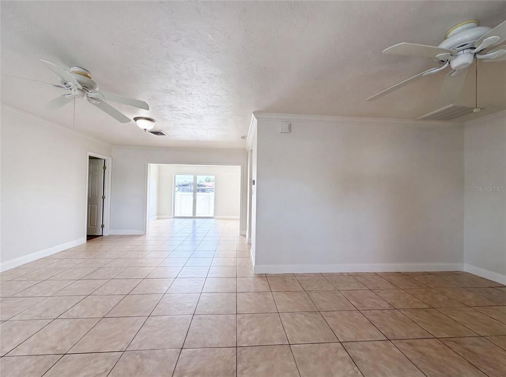 An open-concept living area features light-colored tile flooring, two ceiling fans, and white walls — 1672 JUPITER ROAD, VENICE, FL