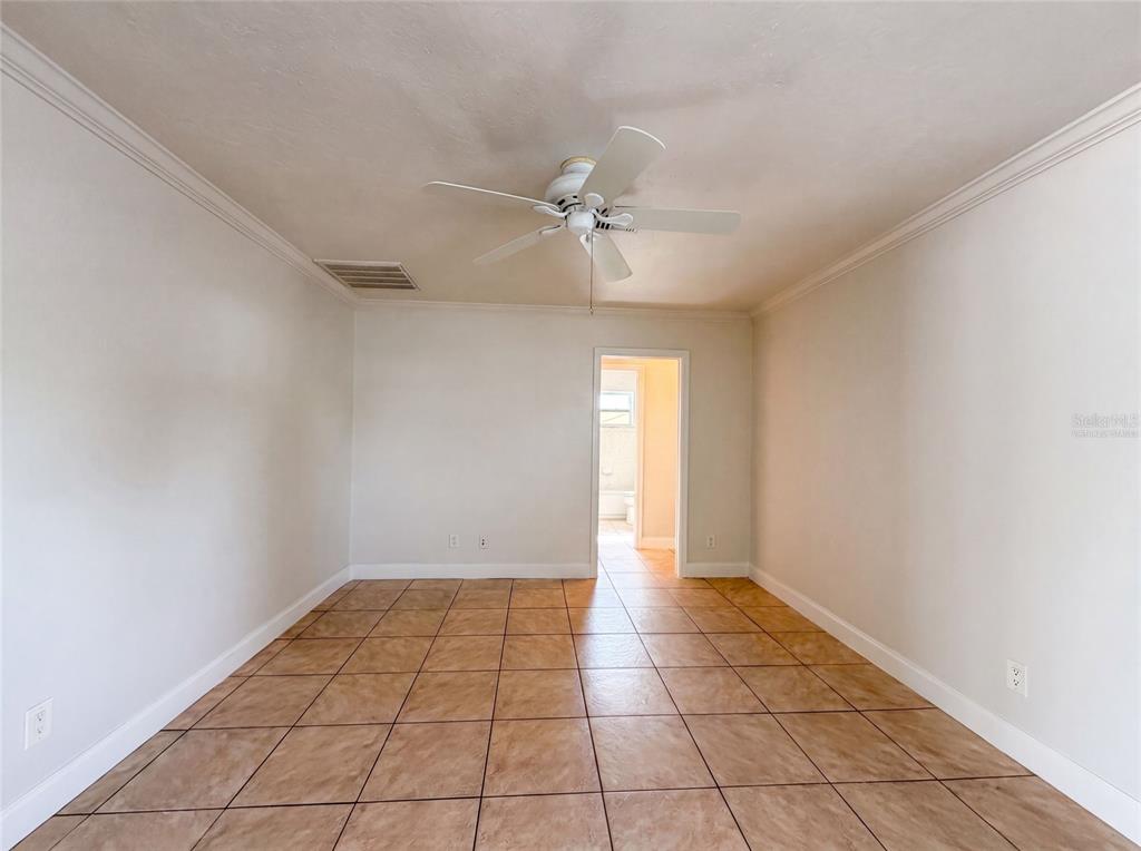 An empty room with beige tile flooring, white walls, and a ceiling fan — 1672 JUPITER ROAD, VENICE, FL