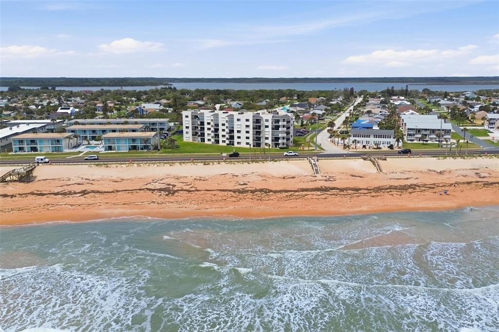 An aerial view shows a beach, a coastal road, and several multi-story residential buildings — 2860 OCEAN SHORE BOULEVARD UNIT 1010, ORMOND BY THE SEA, FL