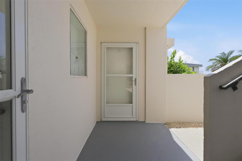 A covered outdoor entryway features a gray floor, a white door, and a side window — 2860 OCEAN SHORE BOULEVARD UNIT 1010, ORMOND BY THE SEA, FL