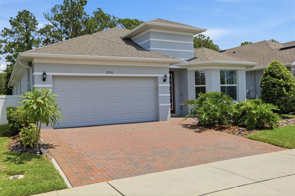 A single-story house with a gray exterior, a two-car garage, and a brick paver driveway — 17932 PASSIONFLOWER CIRCLE, CLERMONT, FL