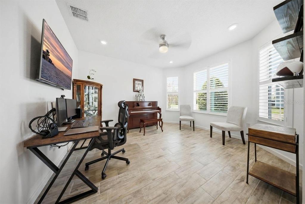 A home office features a desk, a piano, two chairs, and tile flooring — 17932 PASSIONFLOWER CIRCLE, CLERMONT, FL