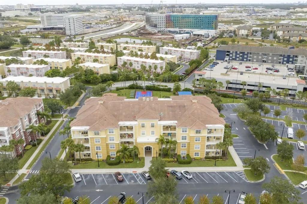 An aerial view shows a multi-story apartment building with a tiled roof and parking lot — 5025 SHOREWAY LOOP UNIT 10703, ORLANDO, FL