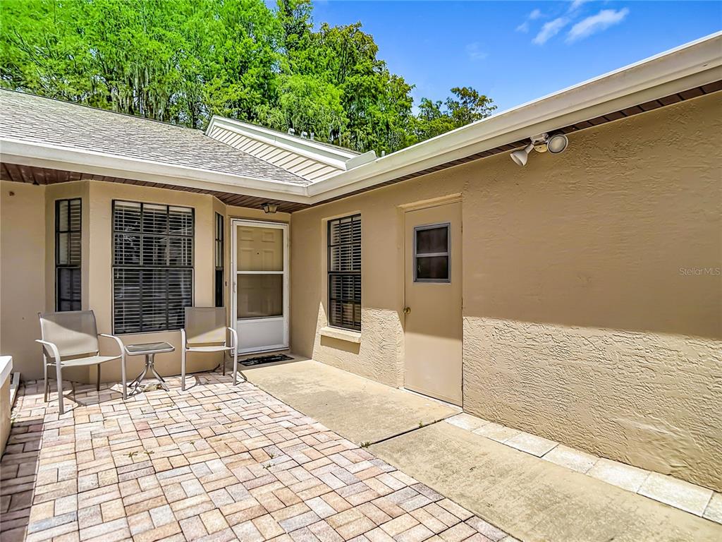 A paved patio sits between two exterior walls with windows and two doors — 13227 MOLITOR COURT, HUDSON, FL