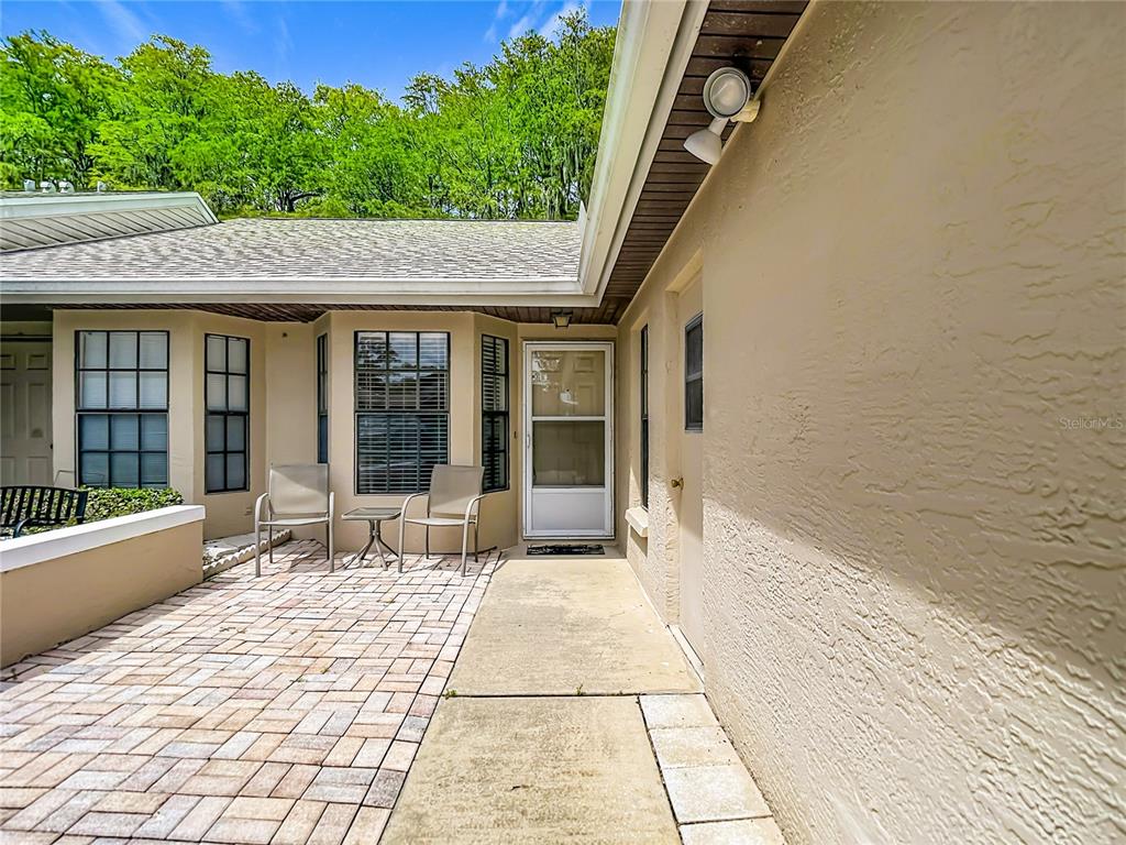 A paved patio area sits outside a home entrance with a white door and windows — 13227 MOLITOR COURT, HUDSON, FL
