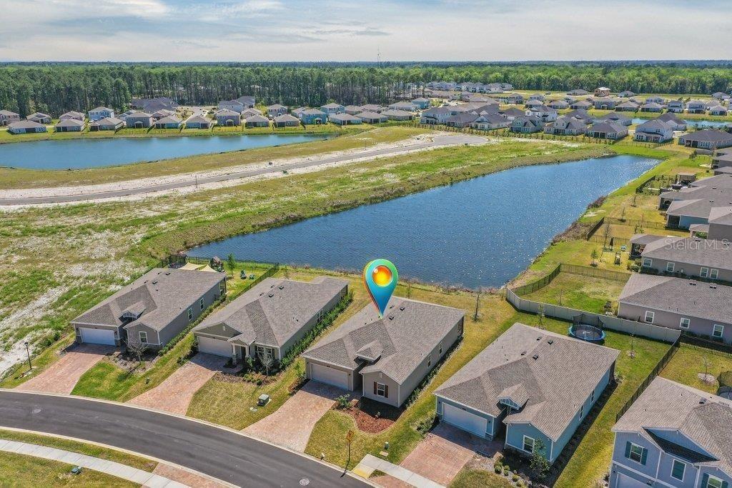 An aerial view shows a suburban house with a pin marker overlooking a retention pond — 210 WHITE RABBIT RUN, ST AUGUSTINE, FL