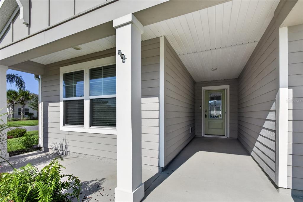 A covered front porch with gray horizontal siding, a white column, and a light green door — 23 PYRITE PLACE, ST AUGUSTINE, FL