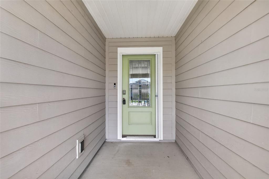 A light green front door is centered in a covered entryway with gray horizontal siding — 23 PYRITE PLACE, ST AUGUSTINE, FL