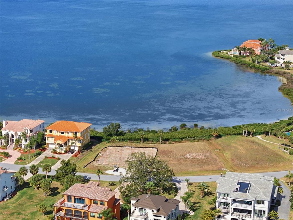An aerial view shows a vacant waterfront lot situated between two large residential homes — 26 HARBORPOINTE DR, PORT RICHEY, FL