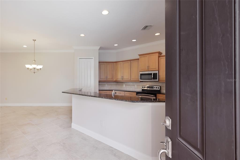 A kitchen with light wood cabinets and a dark granite breakfast bar overlooks a dining area — 6123 25TH STREET E, ELLENTON, FL