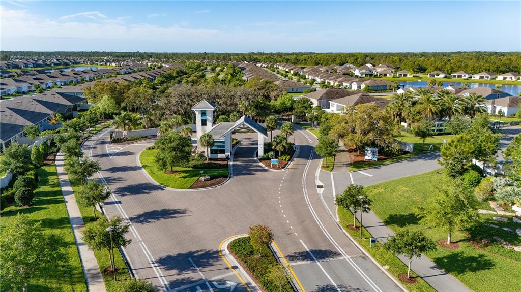 An aerial view shows the gated entrance to a residential neighborhood with surrounding houses — 2873 CHERRY BLOSSOM LOOP, ST CLOUD, FL