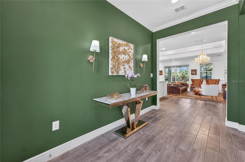 A green-walled entryway features a marble-topped console table, wall sconces, and a view into a living room — 2873 CHERRY BLOSSOM LOOP, ST CLOUD, FL