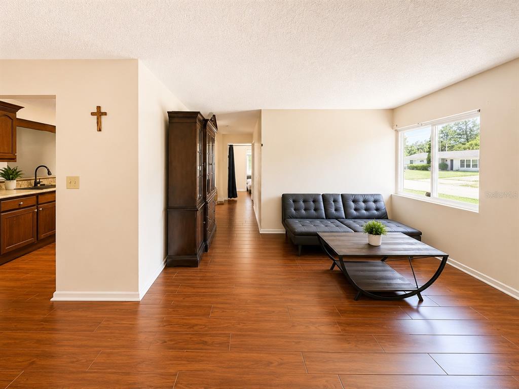 A living room features wood-look flooring, a dark sofa, a coffee table, and a hutch — 934 HILLWOOD DR, DUNEDIN, FL