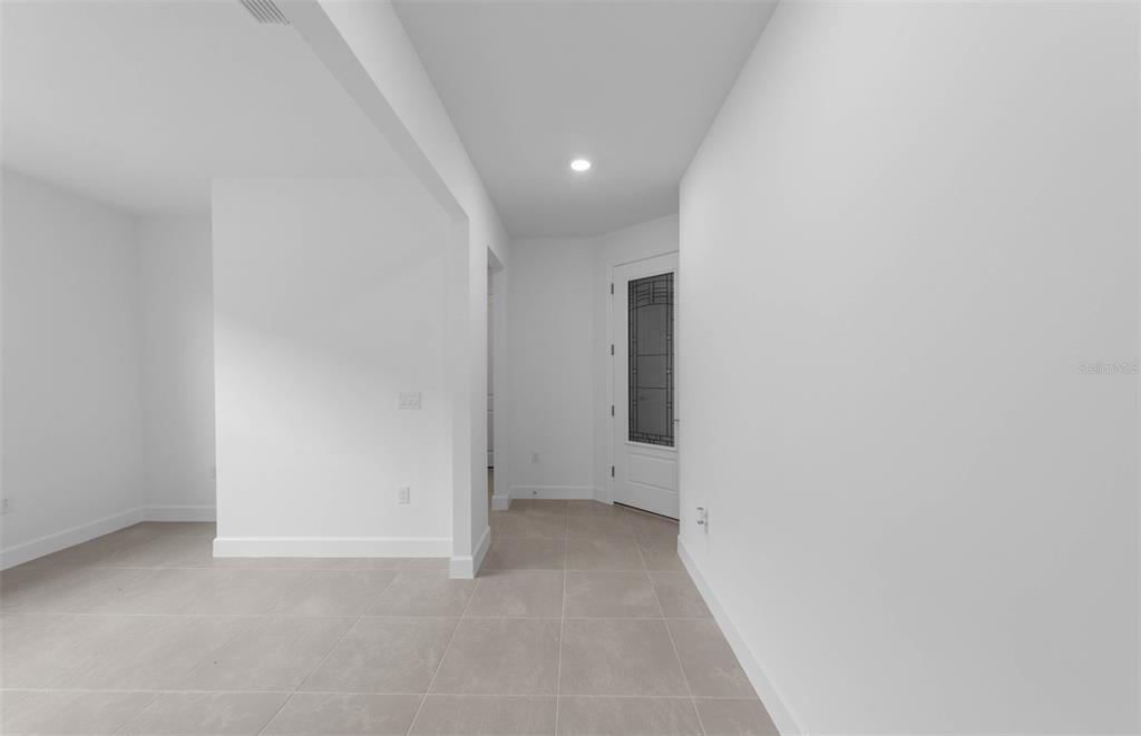 A bright entryway with light-colored tile flooring leads to a white door with glass panels — 1611 TAVIRA PLACE, ENGLEWOOD, FL