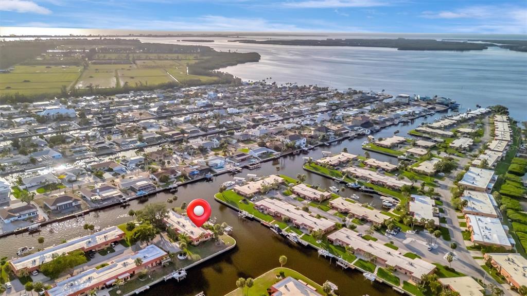 An aerial view shows a waterfront residential neighborhood with canals, docks, and single-story homes — 4096 EL DORADO COVE, BRADENTON, FL