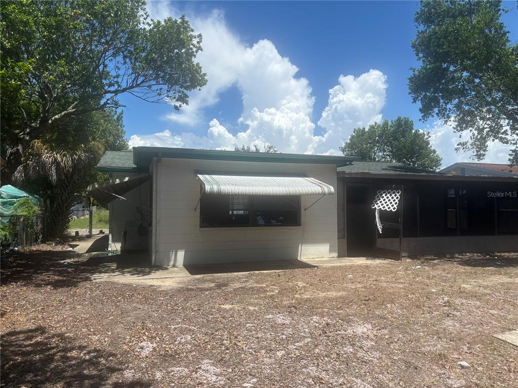 The exterior of a single-story house features a white facade, a striped window awning, and a screened-in porch — 8648 FOX HOLLOW DRIVE, PORT RICHEY, FL