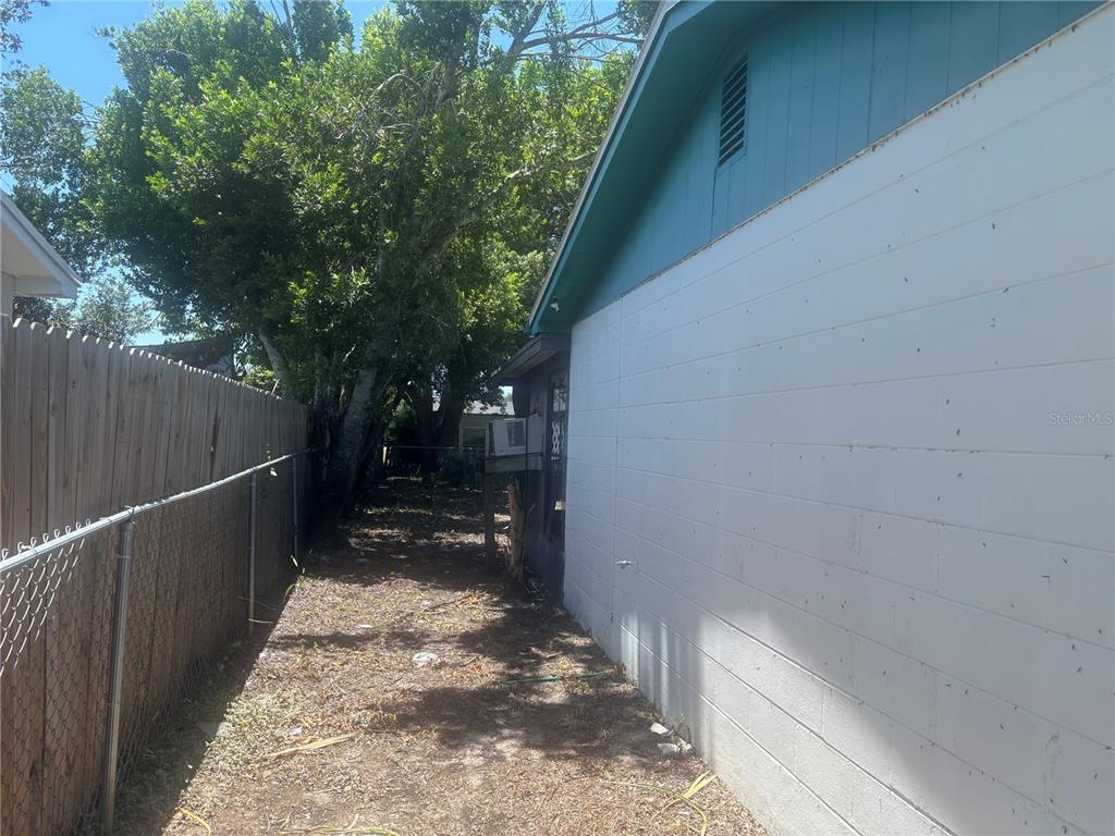 A narrow side yard features a white concrete block wall and a chain-link fence — 8648 FOX HOLLOW DRIVE, PORT RICHEY, FL