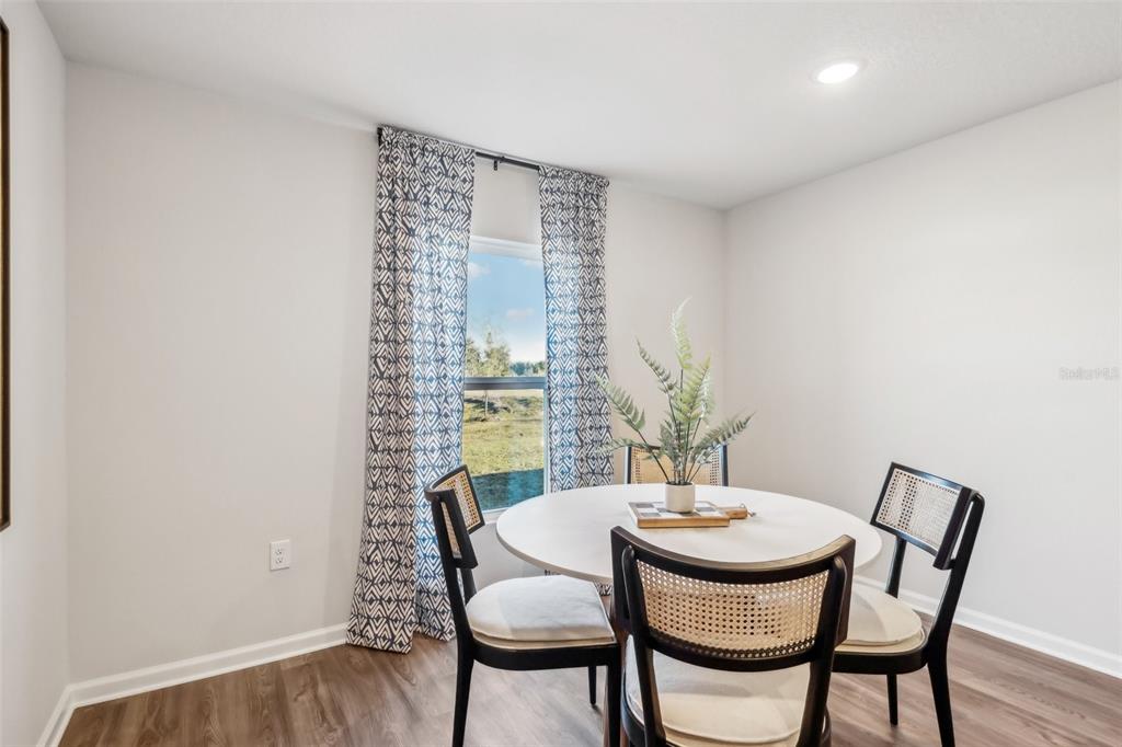 A dining area features a round white table, three chairs, and patterned curtains by a window — 7201 PALOMAR PARKWAY, FORT PIERCE, FL
