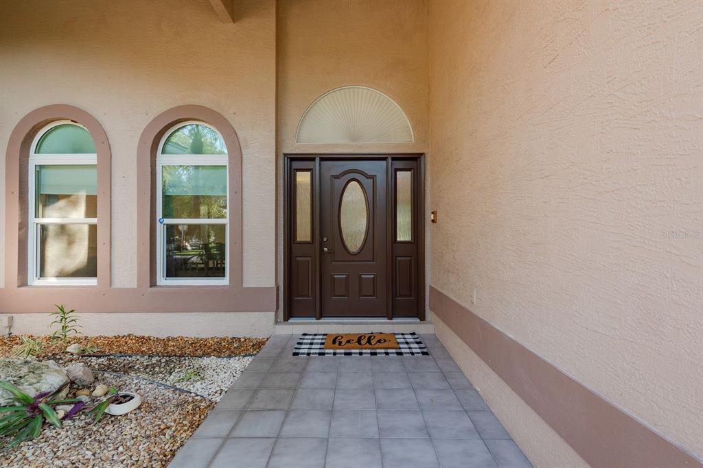 A single-story house with a two-car garage and arched windows at sunset — 771 WEATHERSFIELD DRIVE, DUNEDIN, FL