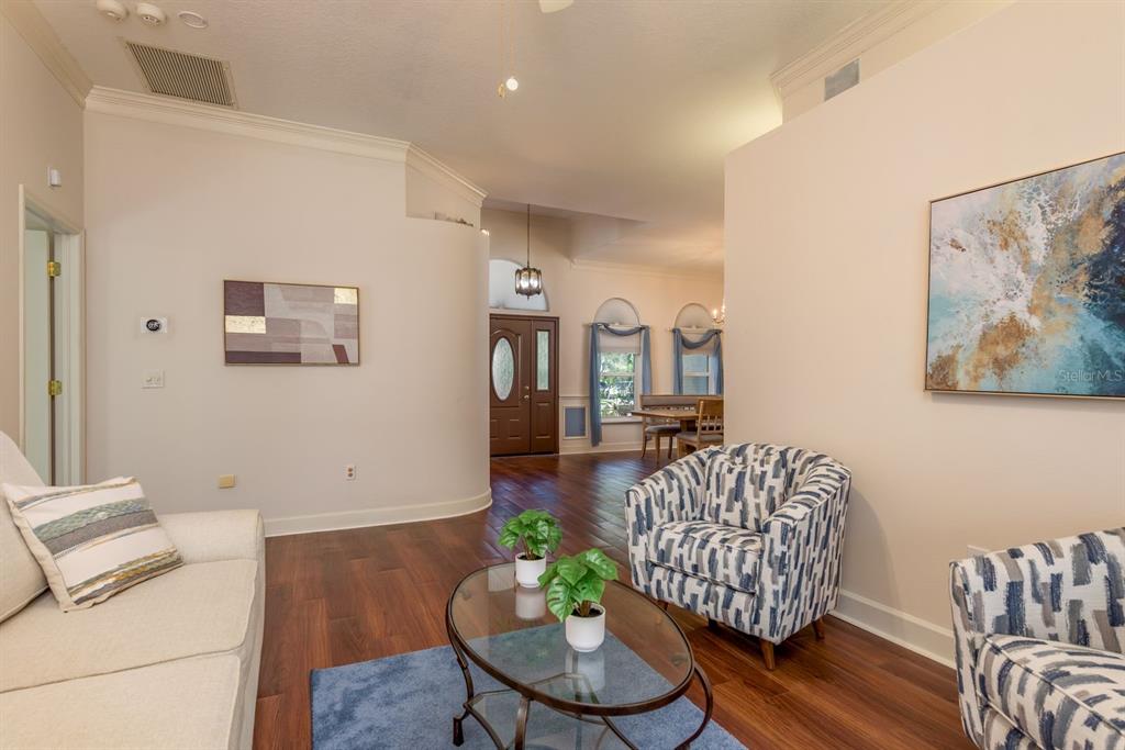 A dining room features a wooden table, chairs, a chandelier, and arched windows with drapes — 771 WEATHERSFIELD DRIVE, DUNEDIN, FL